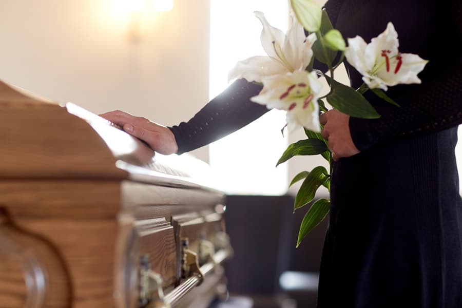 Person by casket with flowers
